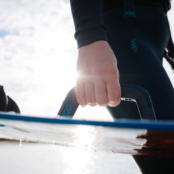 WOO Big Air Handle impugnato su un kiteboard durante una sessione — grip composito nero con alloggio sensore integrato